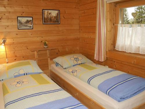 twee bedden in een blokhut met een raam bij Schanzer-Hütte Comfortable holiday residence in Hohentauern