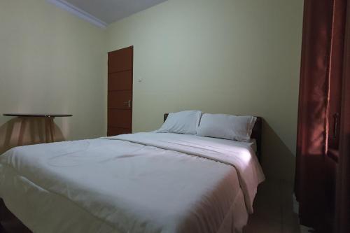 uma cama branca num quarto com um candeeiro em OYO 93912 Kost Takalar 