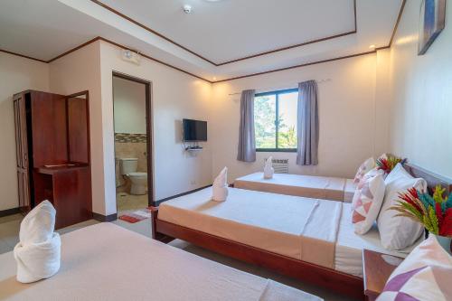 a hotel room with two beds and a window at Dinah's Tourist Inn Puerto Princesa in Puerto Princesa City