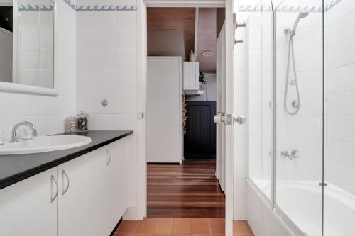 a white bathroom with a shower and a sink at Secluded 3-Bed Retreat Moments to the Beach in Surf Beach