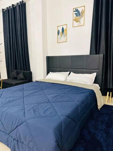 uma grande cama azul num quarto com cortinas pretas em J’s Inn- A petite paradise em Guwahati