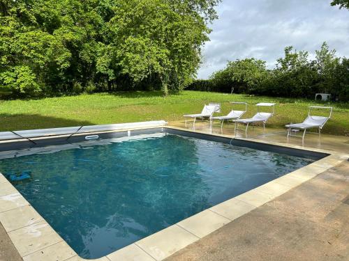 a swimming pool with chairs in a yard at LE PARC in Coulanges-sur-Yonne