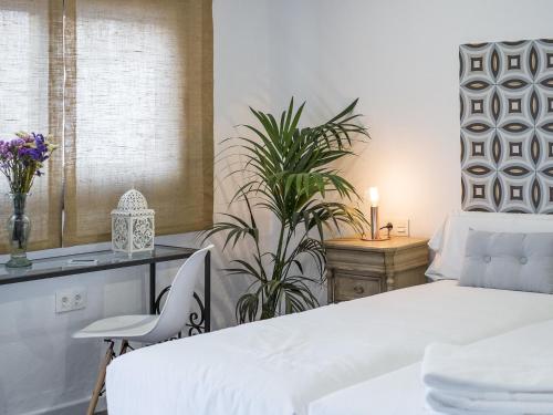セビリアにあるSelecta Apartments Los Venerablesの白いベッドと植物が備わるベッドルーム1室が備わります。