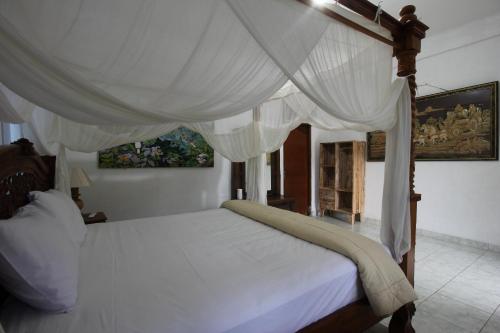 1 dormitorio con 1 cama blanca con dosel en Belvilla 93916 Budi House Near Ubud Palace, en Ubud