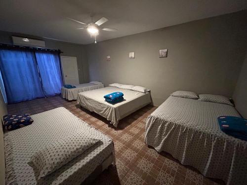 a bedroom with three beds and a ceiling fan at Villas La Romana #2 in La Ceiba