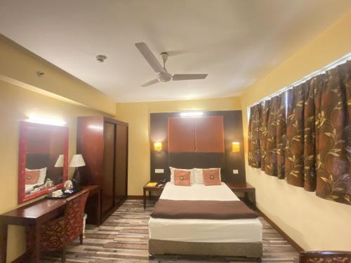 a hotel room with a bed and a ceiling fan at Astoria Hotel in Kolkata