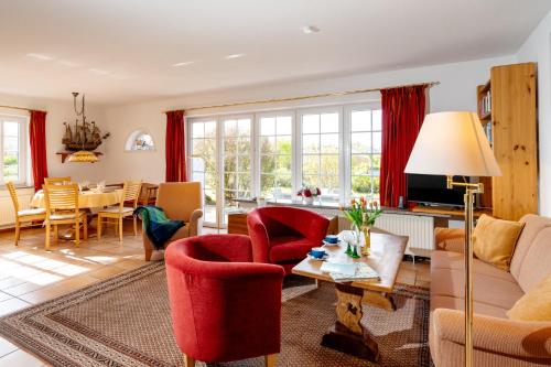 sala de estar con sillas rojas y mesa en Haus Jölhuk, en Morsum