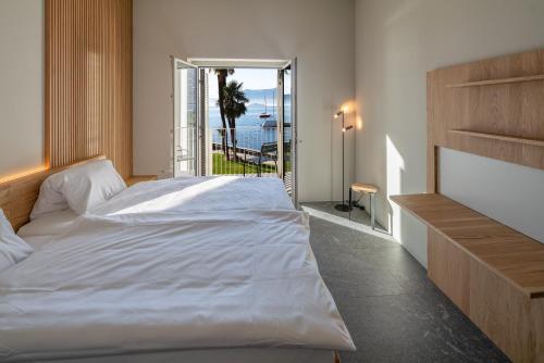 una camera con un grande letto bianco e un balcone di Casa Moscia ad Ascona