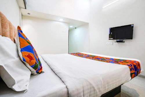 a small bedroom with a bed and a flat screen tv at FabHotel Saroj Inn in Nashik