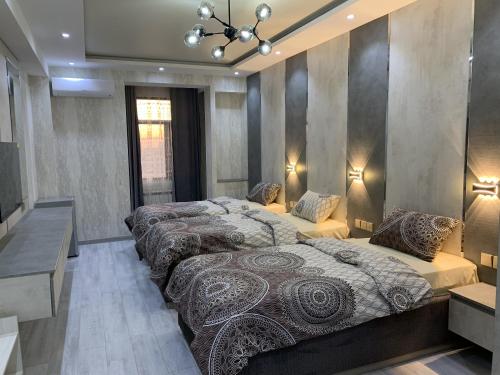 - 2 lits dans une grande chambre avec des lumières sur le mur dans l'établissement Firdavsi Hotel, à Douchanbé