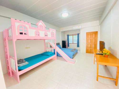 ein rosafarbenes Etagenbett in einem Zimmer mit einem Schreibtisch in der Unterkunft พีพี วิลล่า บางแสน รีสอร์ท in Ban Bang Saen (1)