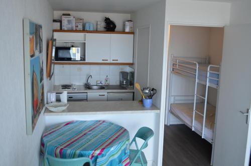 a small kitchen with a sink and a counter with chairs at Grand studio face mer baie de la Baule avec terrasse proche Thalasso et Parking in Pornichet