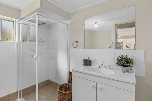 a white bathroom with a shower and a sink at Carrickalinga SeaHaven in Normanville