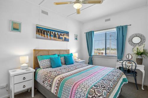 Un dormitorio con una cama con almohadas azules y una ventana. en Carrickalinga SeaHaven, en Normanville