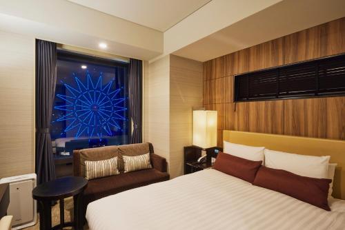 a bedroom with a bed and a chair and a window at Solaria Nishitetsu Hotel Kagoshima in Kagoshima