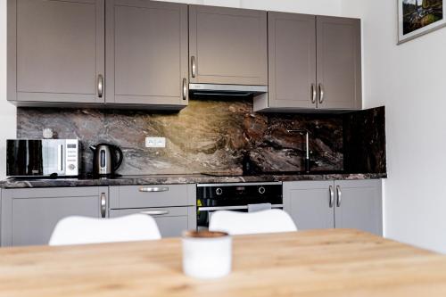 a kitchen with gray cabinets and a wooden table at Apartmán v centru Železné Rudy se zahrádkou in Železná Ruda