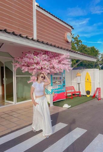 a woman standing in front of a playground with pink flowers at พีพี วิลล่า บางแสน รีสอร์ท in Ban Bang Saen (1)