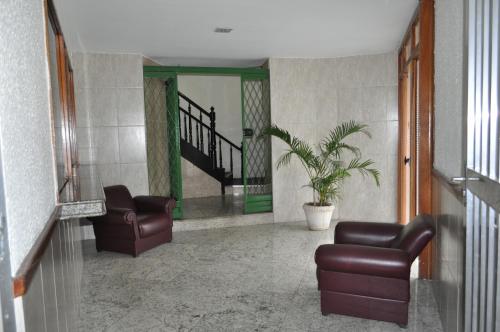 a living room with two chairs and a plant at Parque Hotel in Rio de Janeiro