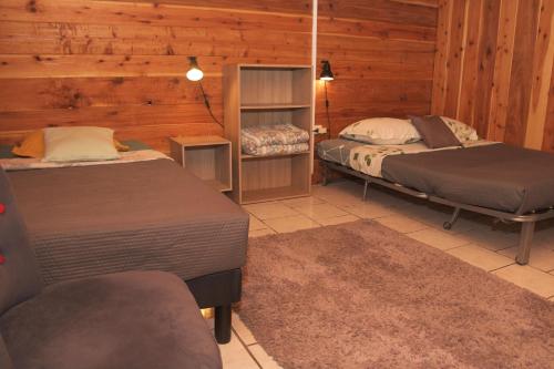 two beds in a room with wooden walls at Le Chalet à Joel in Cilaos
