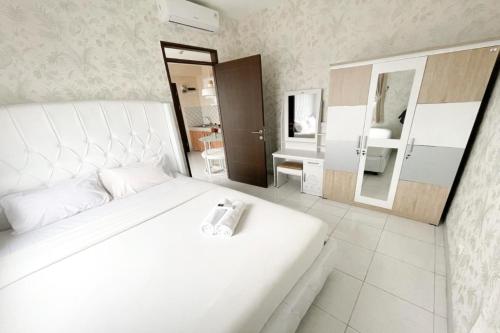 Dormitorio blanco con cama blanca y espejo en OYO 93940 Apartemen Mekarwangi Square By Lina en Bandung