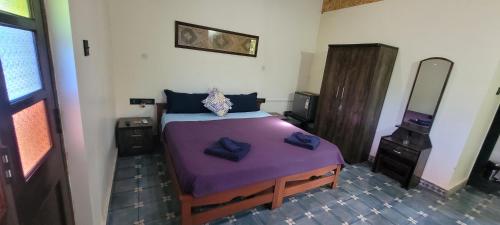 een slaapkamer met een groot bed met paarse lakens bij Villa Agastya in Betalbatim