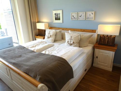 ein Schlafzimmer mit einem großen Bett mit weißer Bettwäsche und Kissen in der Unterkunft Gode Wind Quartiere 2 in Dahme