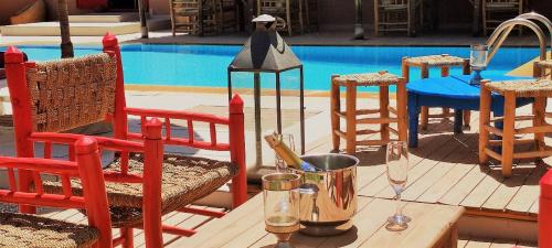 a table with wine glasses and chairs next to a pool at Jenny Lynn in Marrakech