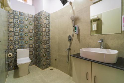 uma casa de banho com um lavatório, um chuveiro e um WC. em ArtBuzz Rishikesh em Rishikesh