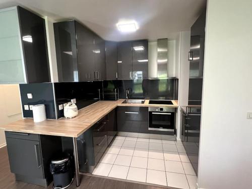 une cuisine avec des armoires noires et un comptoir en bois dans l'établissement Ds appartement élégant au pieds du tramway, à Vitry-sur-Seine