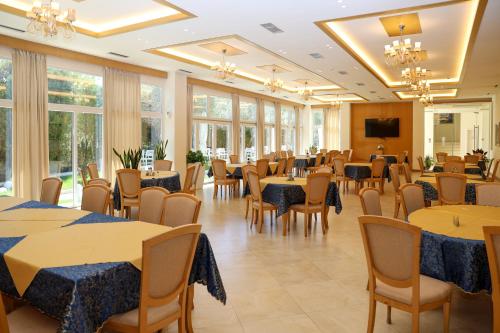 a dining room with tables and chairs and windows at Grand White City Hotel in Berat