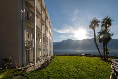 a building with palm trees and the sun in the background at Casa Moscia in Ascona