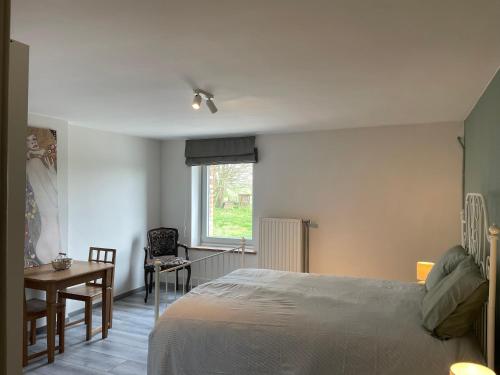 a bedroom with a bed and a table and a window at Eole - Fermette typique Ardennaise in Sainte-Ode