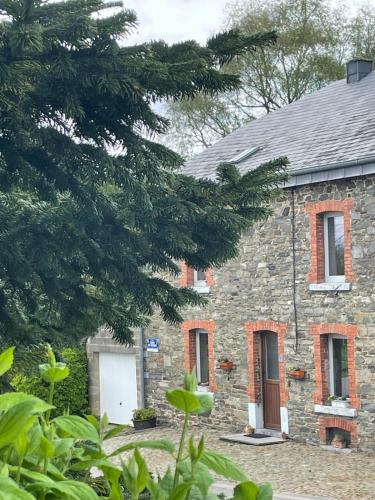 a stone house with a white door and windows at Eole - Fermette typique Ardennaise in Sainte-Ode