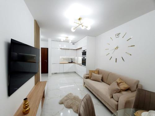 uma sala de estar com um sofá e um relógio na parede em Apartament w Centrum em Grodzisk Mazowiecki