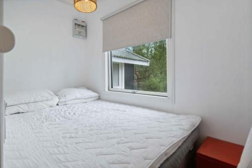 Habitación blanca con cama y ventana en Holiday Home Near Beautiful White Sandy Beaches,, en Gedser