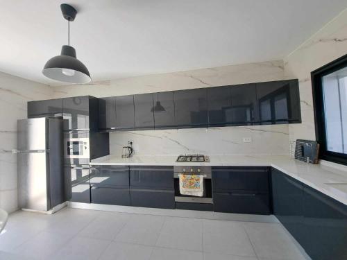 a kitchen with black and white cabinets and a refrigerator at Relaxing Villa with pool in El Haouaria