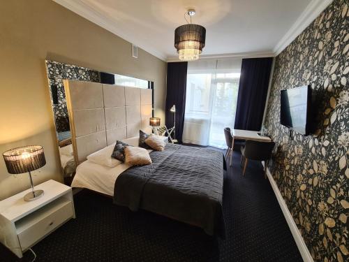 um quarto com uma cama, uma secretária e uma janela em Hotel Kurpia Arte em Nowogród