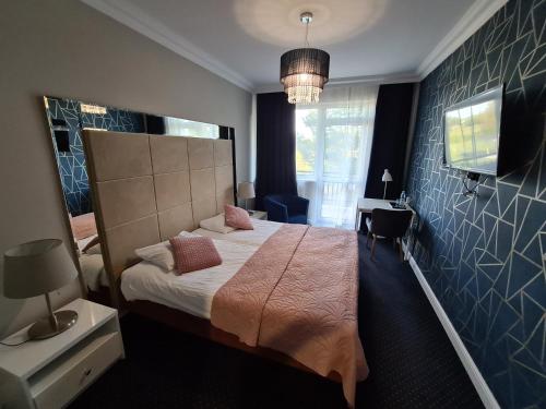 um quarto com uma cama grande e uma televisão em Hotel Kurpia Arte em Nowogród