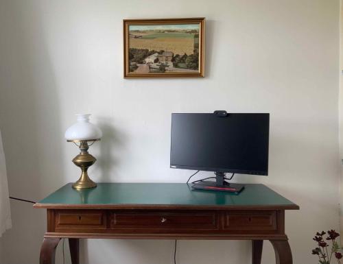a desk with a monitor and a lamp on it at Holiday Home In Poulsker in Neksø