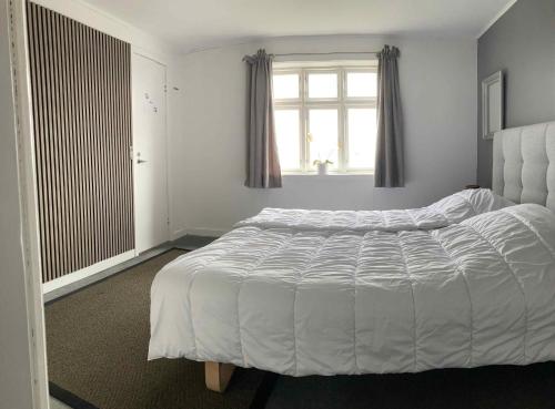 1 cama blanca en un dormitorio con ventana en Holiday Home In Poulsker en Neksø