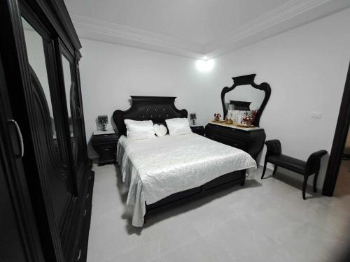 a bedroom with a black and white bed and a mirror at Relaxing Villa with pool in El Haouaria