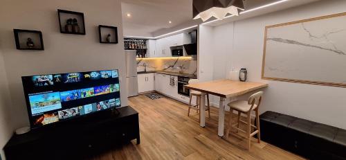 un salon avec une table et une télévision et une cuisine dans l'établissement Maison Duplex - Proche de Paris, à Épinay-sur-Seine
