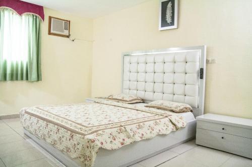 Hotel Belle Cote في أبيدجان: غرفة نوم مع سرير أبيض مع اللوح الأمامي كبير