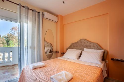 a bedroom with a bed with orange walls and a window at Betty seaside villa in Pefkochori