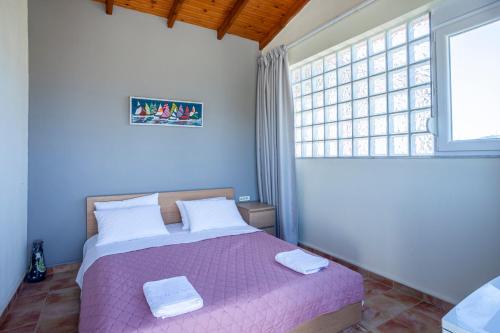 a bedroom with a bed with a purple comforter and a window at Betty seaside villa in Pefkochori