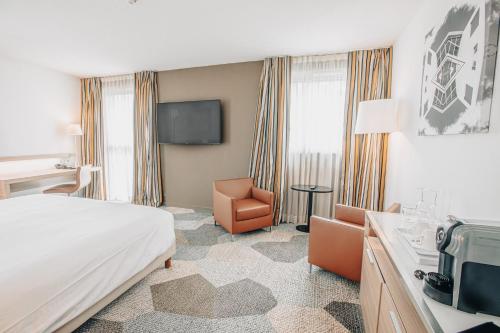 a hotel room with a bed and a chair at Holiday Inn Mulhouse by IHG in Mulhouse
