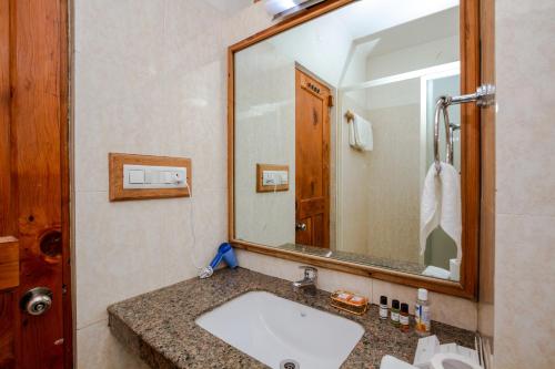 uma casa de banho com um lavatório e um espelho grande em JJ By Vivaan Resort em Shamshi