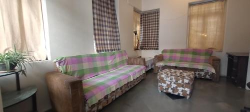 sala de estar con 2 sillas y mesa de centro en Madhav Bhavan Guest House, en Pune