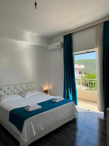 sypialnia z dużym łóżkiem i dużym oknem w obiekcie Villa August Ksamil w mieście Ksamil