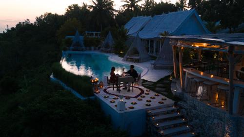 a couple sitting next to a pool at dusk at Atalaya Villas Nusa Penida - Adults only in Nusa Penida